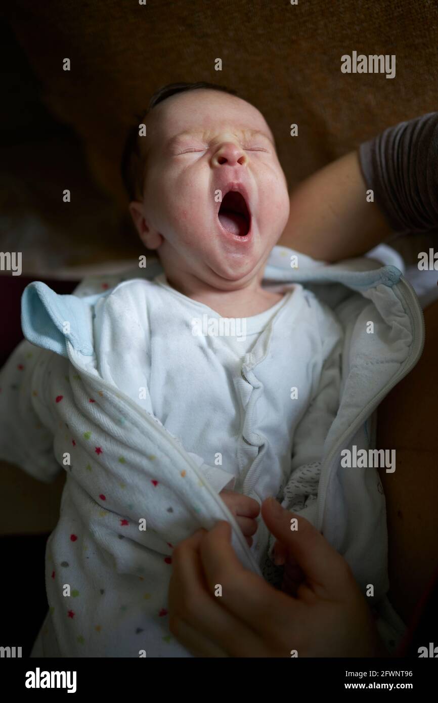Little newborn baby yawning in her mothers lap Stock Photo