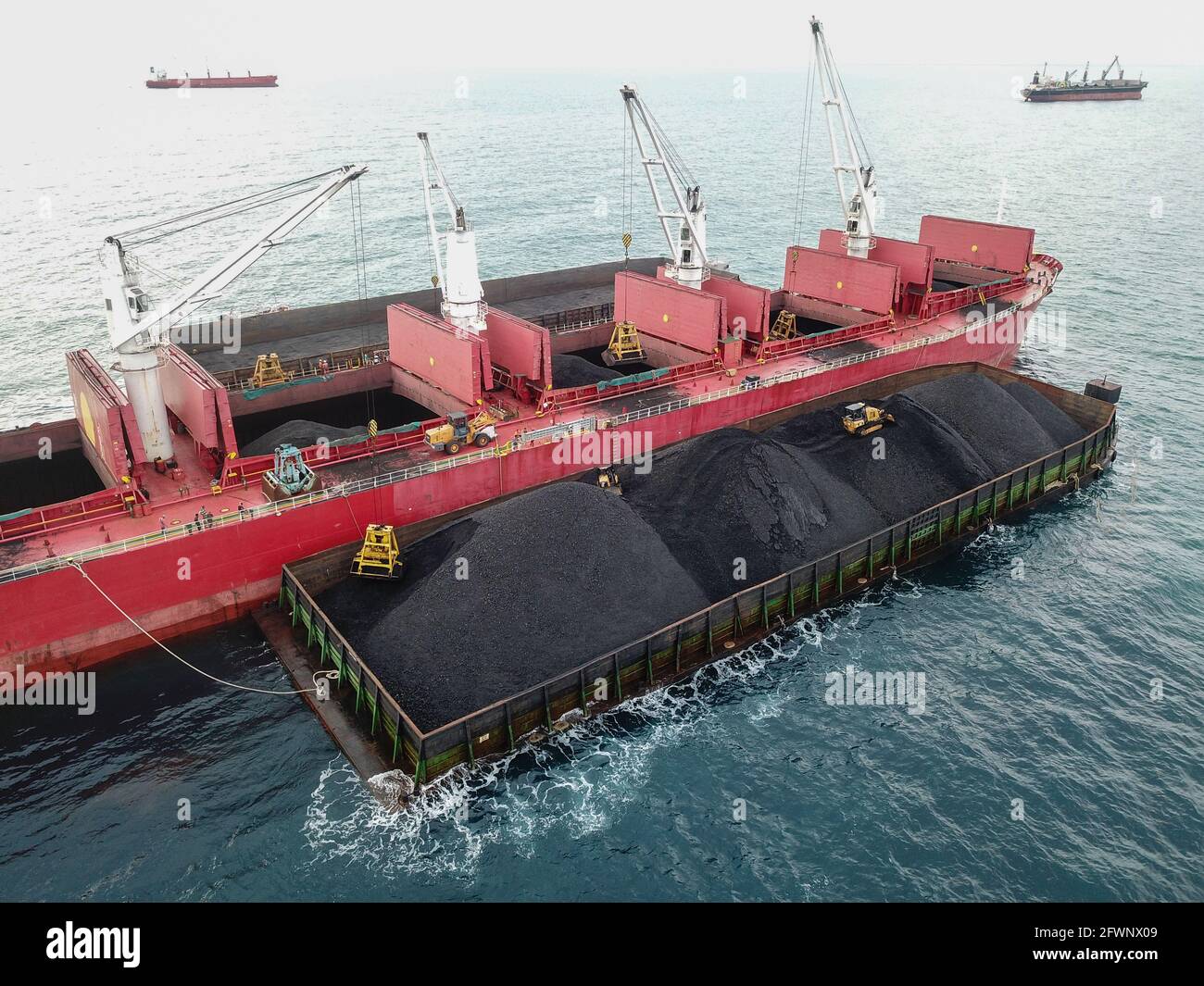 Transporting coal from the barge to the mother vessel aerial view Stock