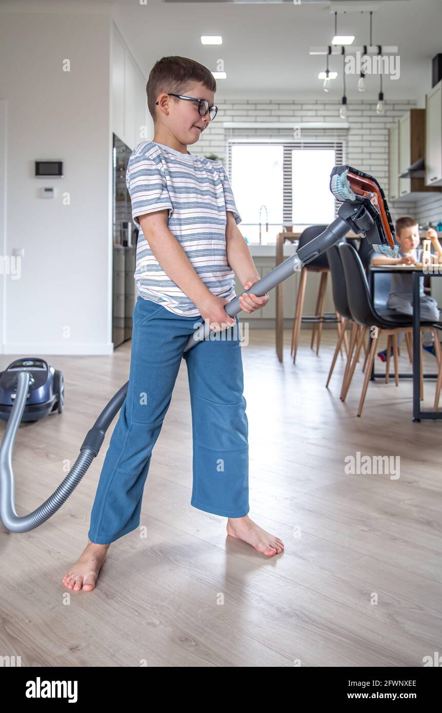 A little boy with glasses is having fun and cleaning the house with a ...