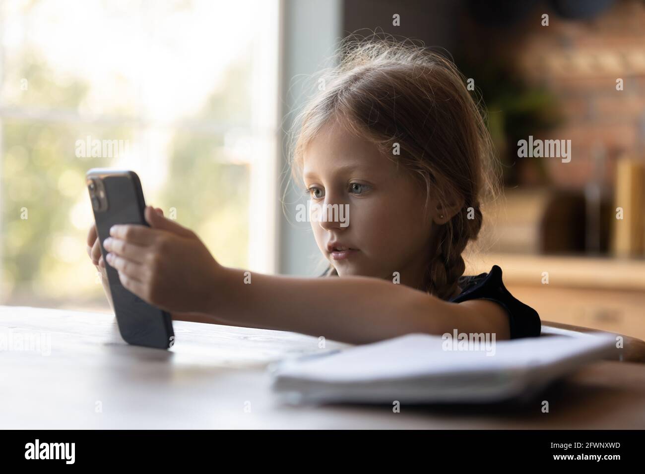 Focused little girl using smartphone for video call Stock Photo