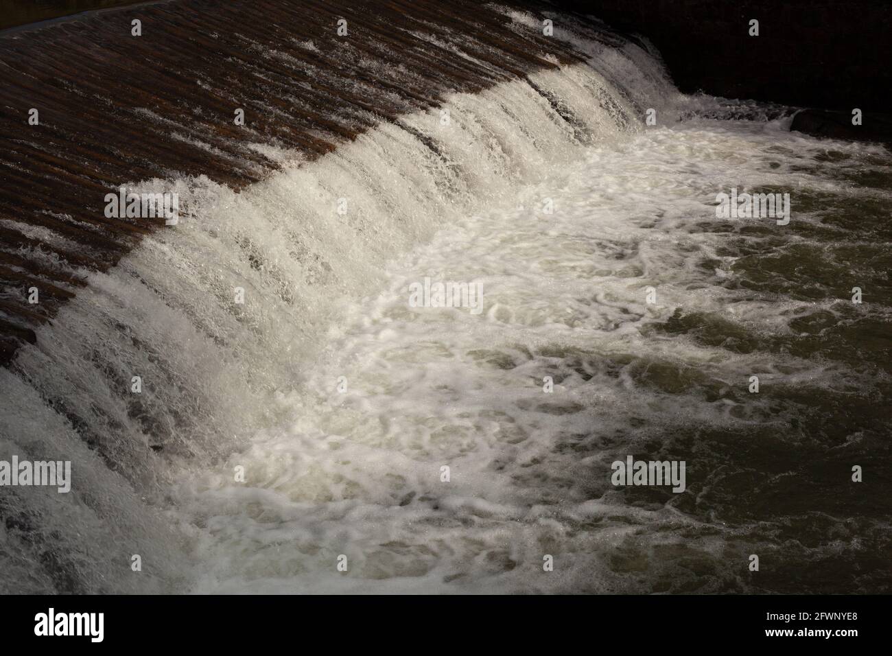A spillway with white water, close-up of the center of the fall and the bubbling water. Stock Photo