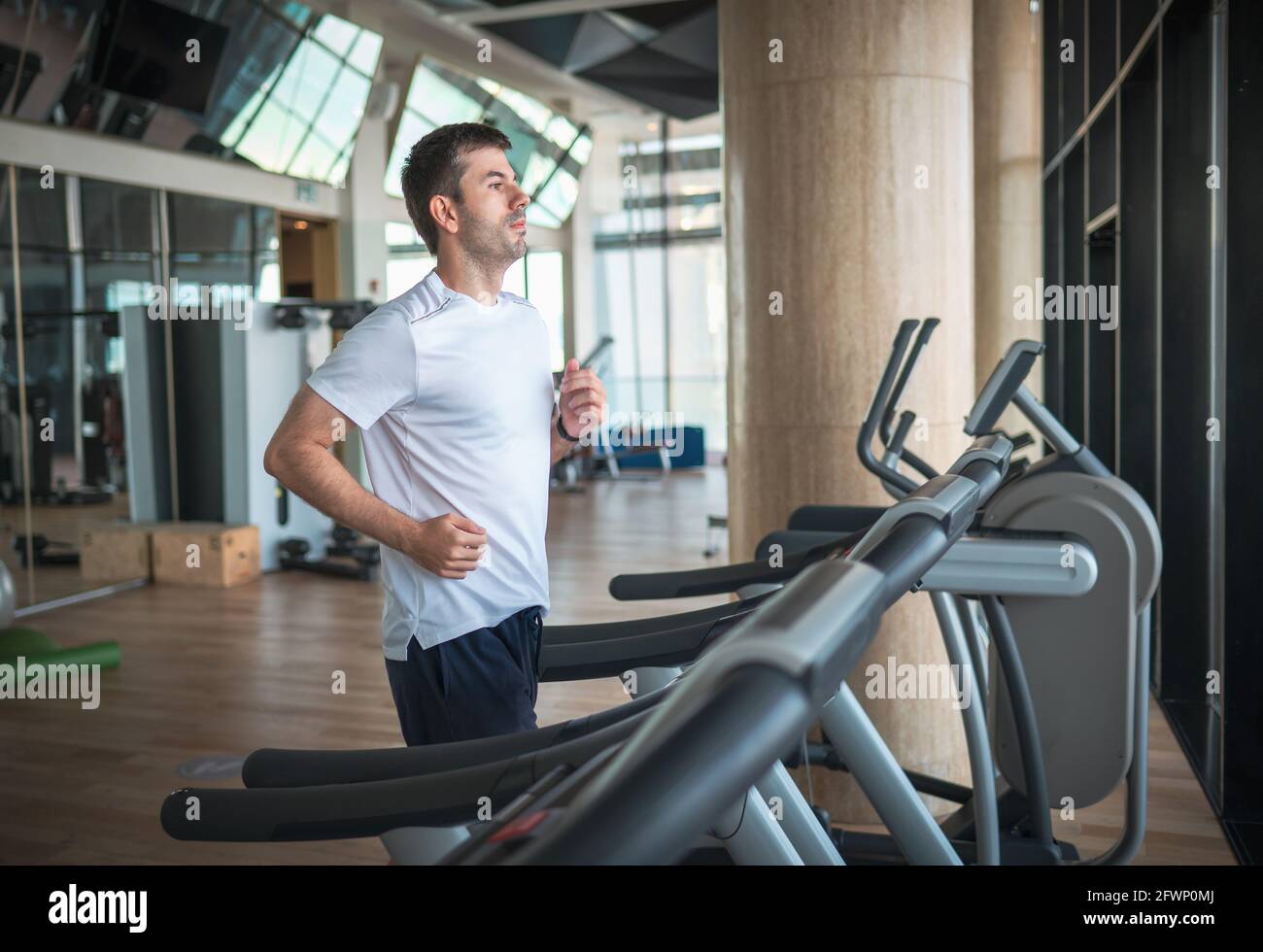 Man jogging on a treadmill during a cardio running warmup exercise in