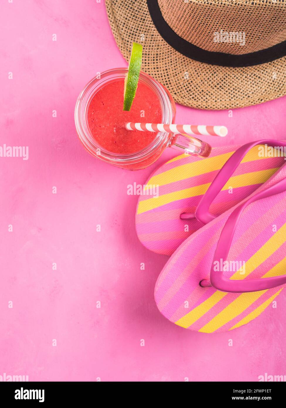 Straw hat, fli flops and red smoothie on pink Stock Photo