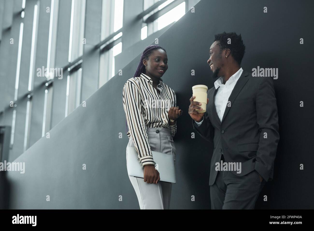 Low angle portrait of two African-American business people chatting in office hall, black and white pattern, copy space Stock Photo