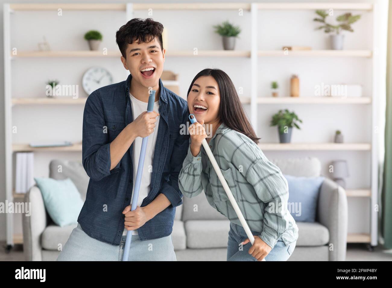 Positive chinese lovers having fun while cleaning house Stock Photo