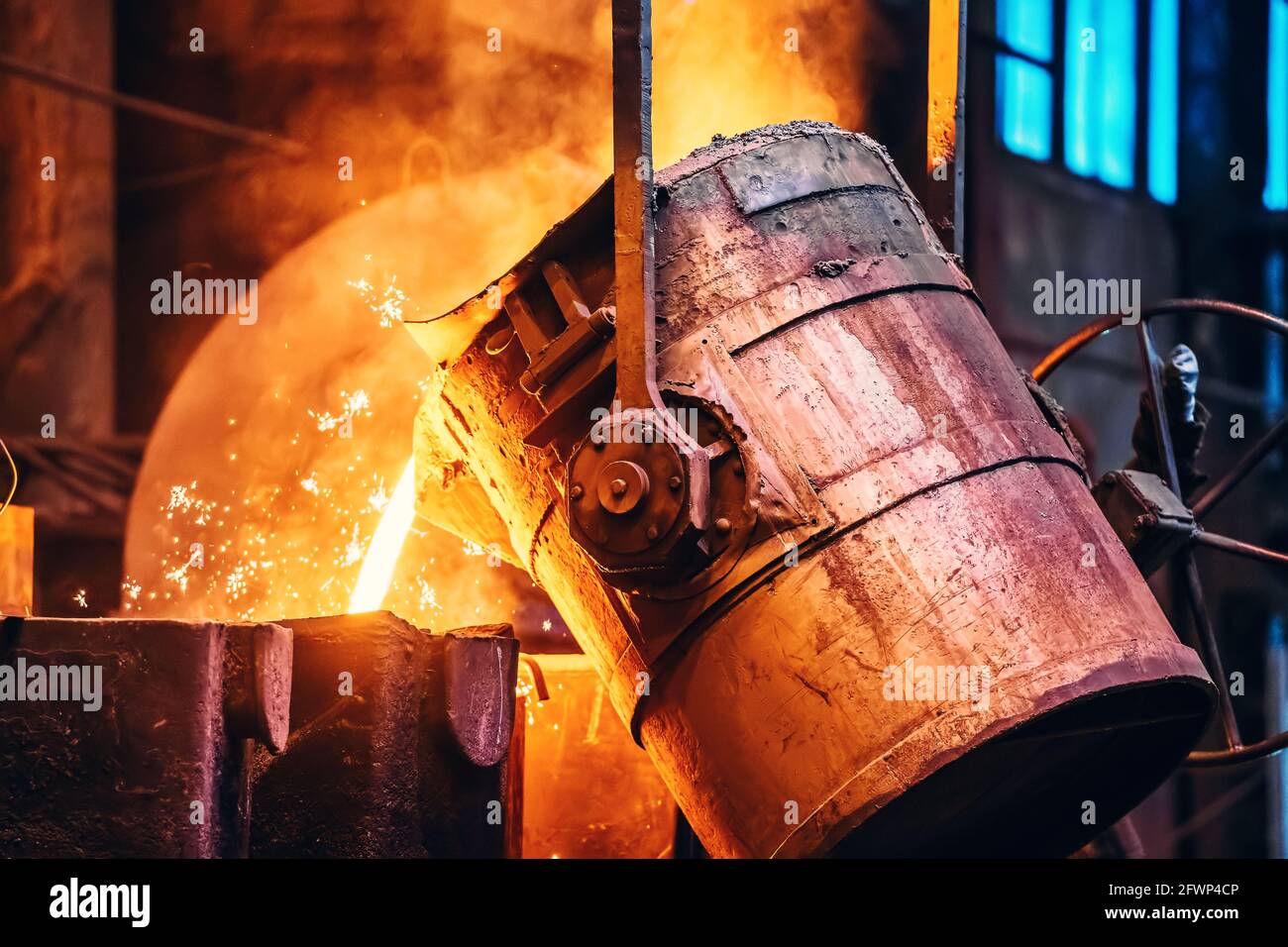 Molten metal pour from ladle Into sand mold. Iron casting process in metallurgy foundry plant, heavy industry. Stock Photo