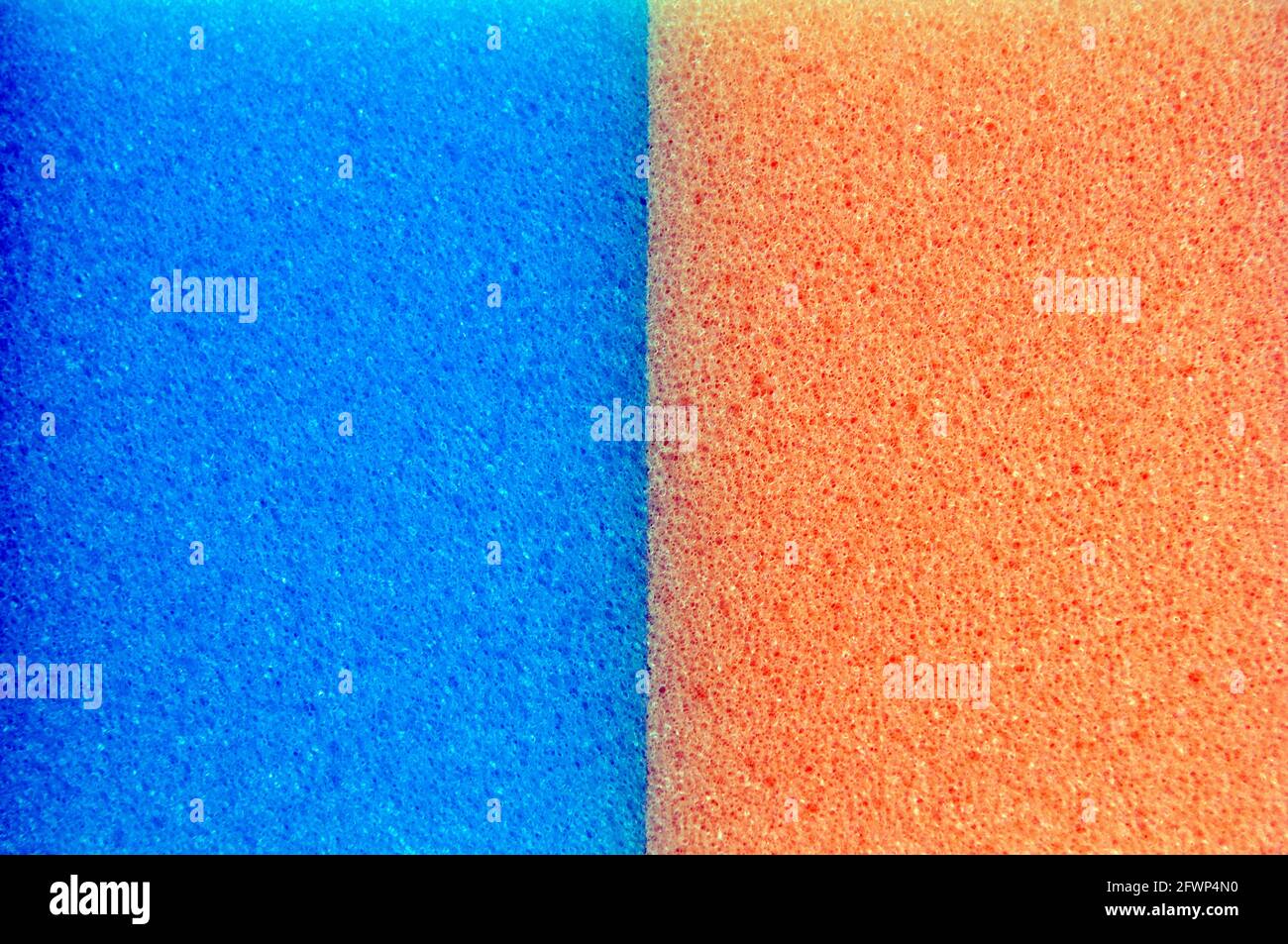 A Close Up Shot Of Two Washing Up Sponges, One Blue and One Orange, Next To Each Other Stock Photo