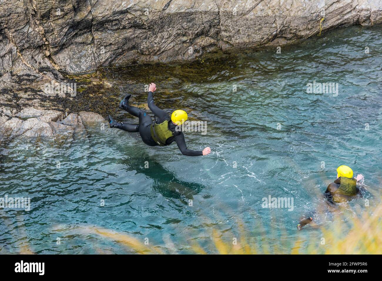 Two holidaymakers on a coasteering session around Towan Head in Newquay in Cornwall. Stock Photo