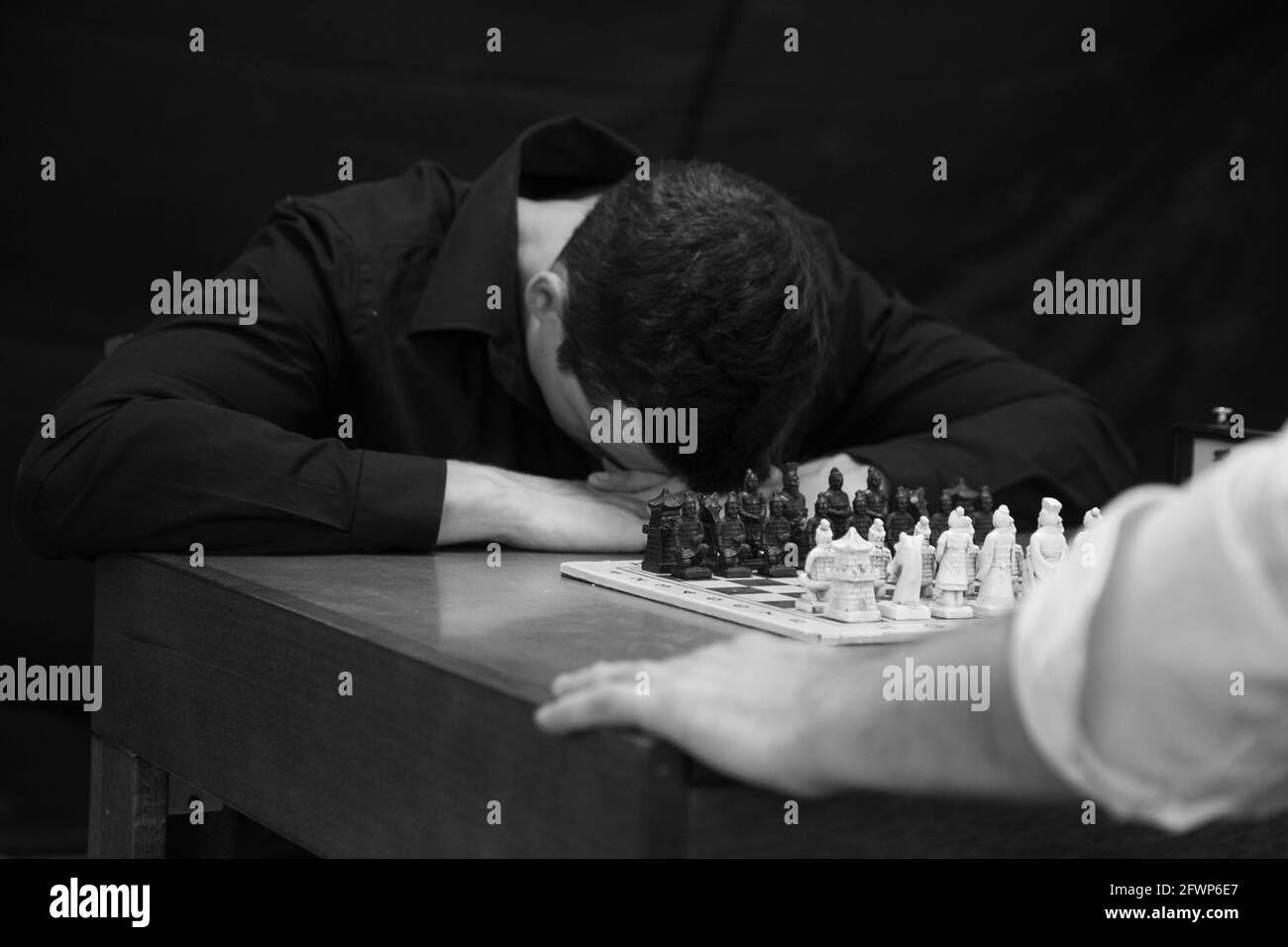 Grayscale shot of two people at the table playing chess Stock Photo