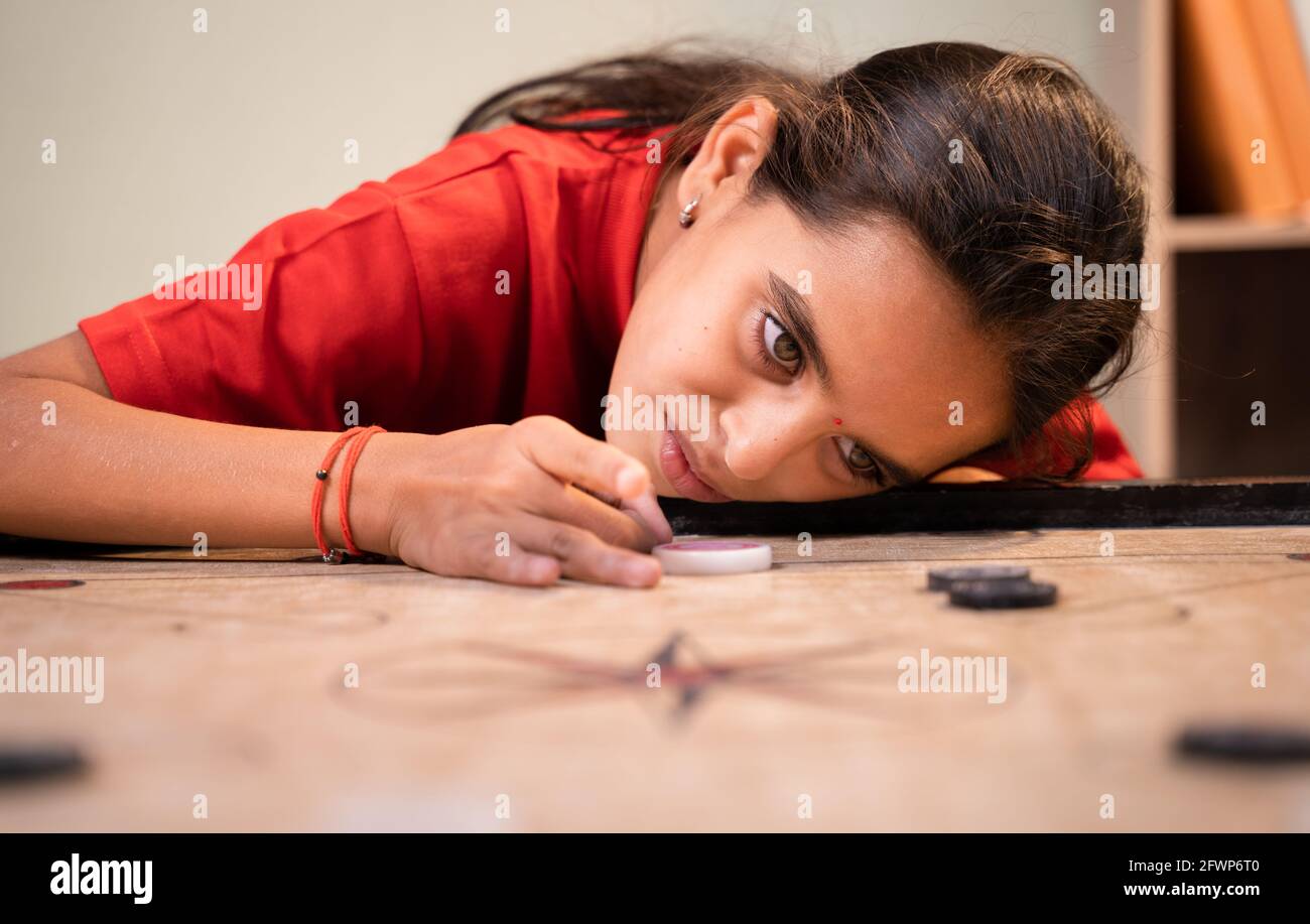 Lazy kid playing carrom by sleeping on board - concept of boredom , brain development and childhood lifestyle Stock Photo