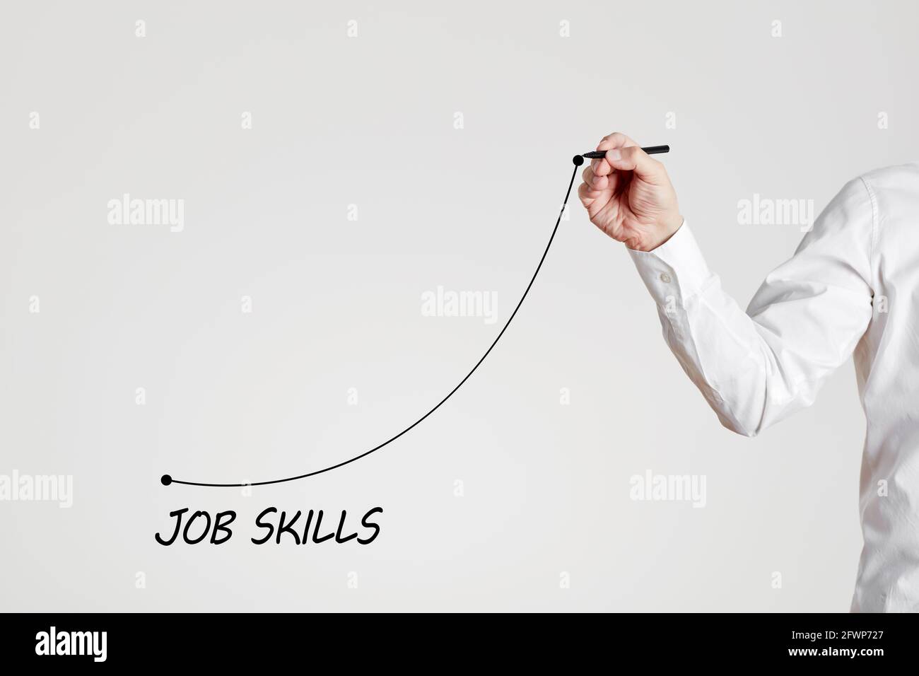 Businessman hand draws a rising line with the word job skills. Increasing business job skills with training or experience concept. Stock Photo