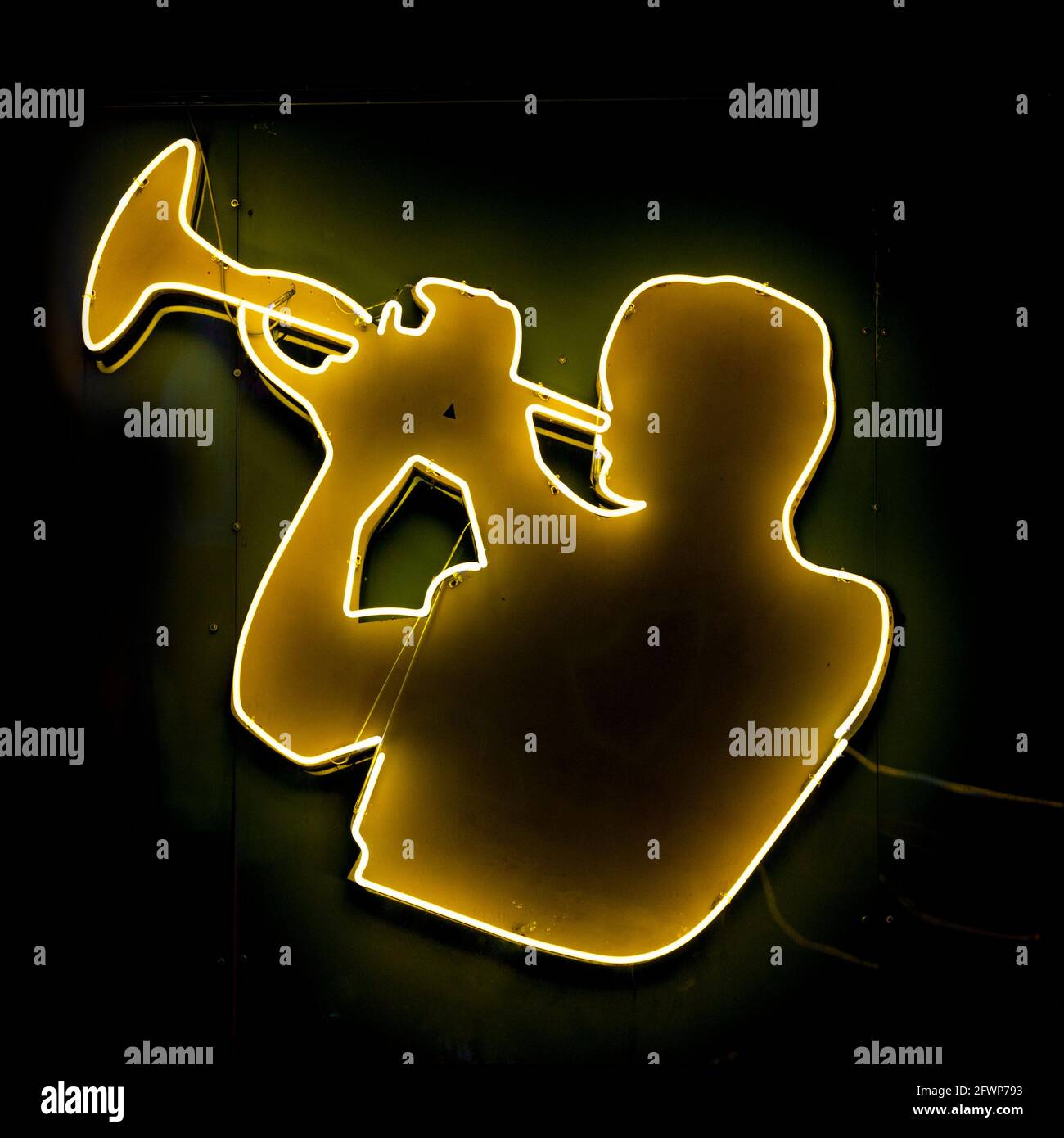 Close-up on a yellow neon light shaped into a trumpeter. Stock Photo