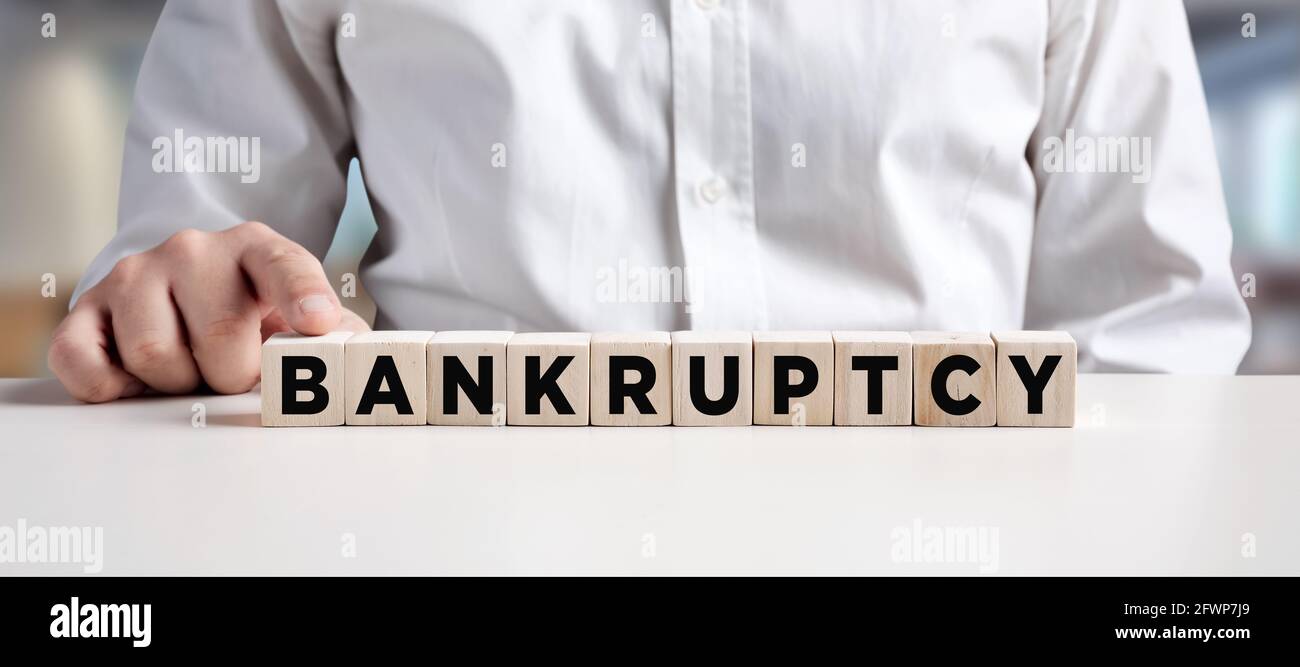Businessman pressing his finger on the wooden cubes with the word bankruptcy. Declaration of bankruptcy. Stock Photo