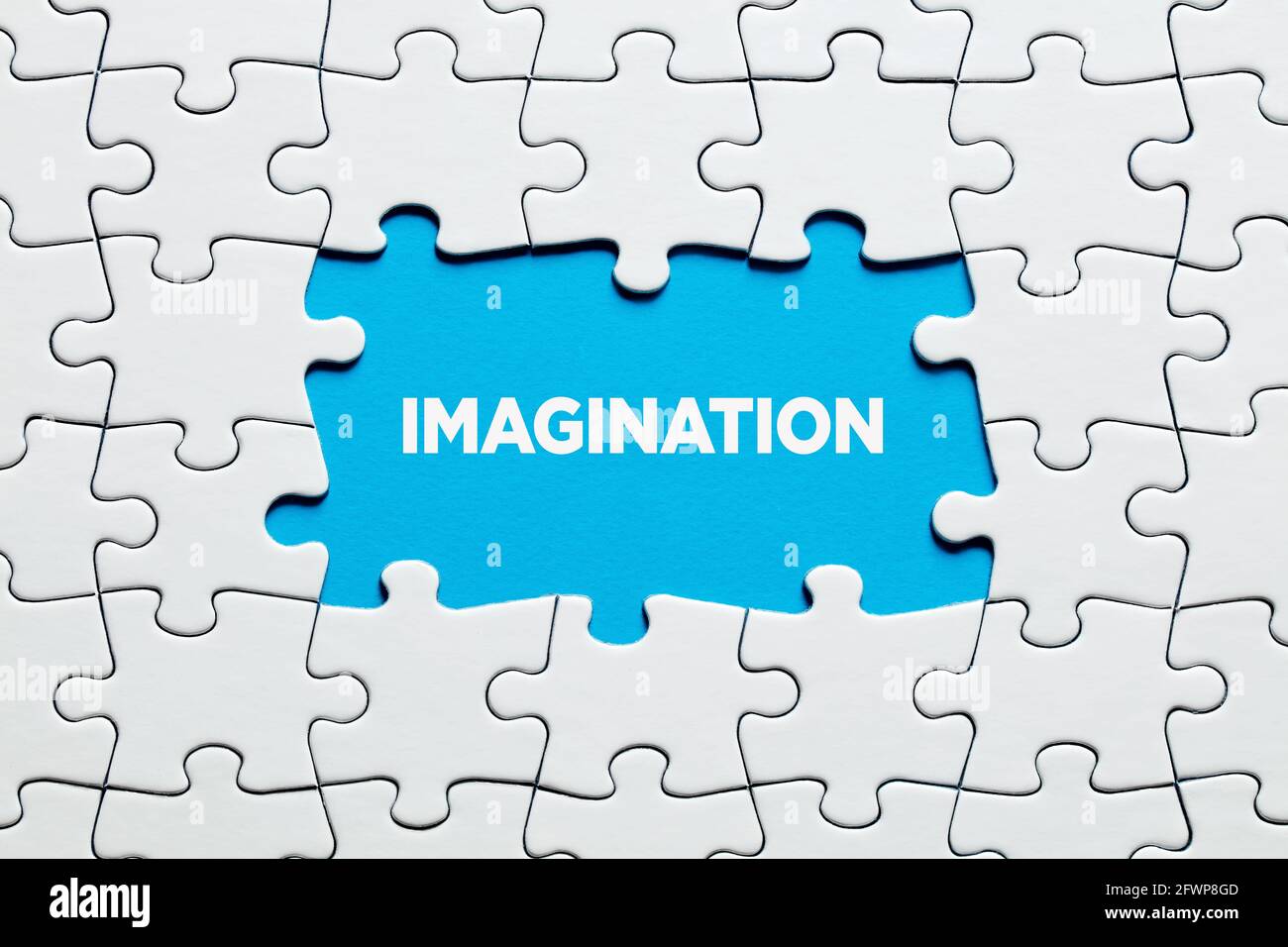 The word imagination on blue background surrounded by jigsaw puzzle. To increase or improve creativity and imagination in education or business. Stock Photo