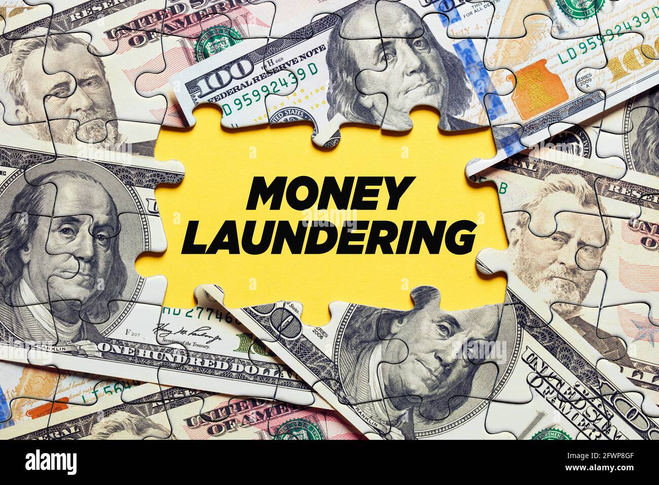 The word money laundering surrounded by puzzle pieces with dollar bill