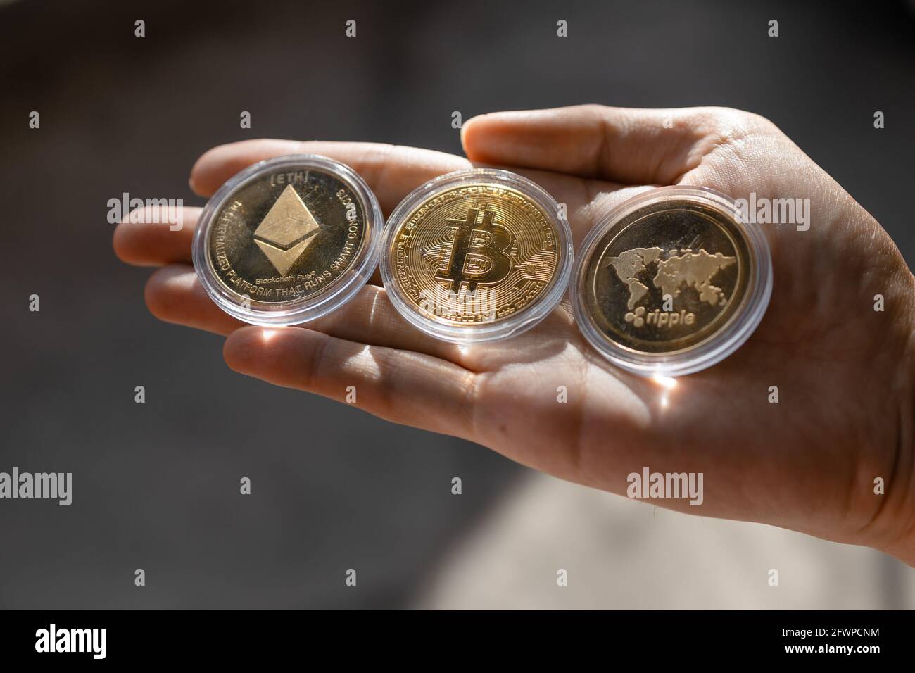 Young man holding Crypto tokens Bitcoin, Ethereum, Ripple on palm of hand -  Cryptocurrency and Digital asset concept Stock Photo - Alamy