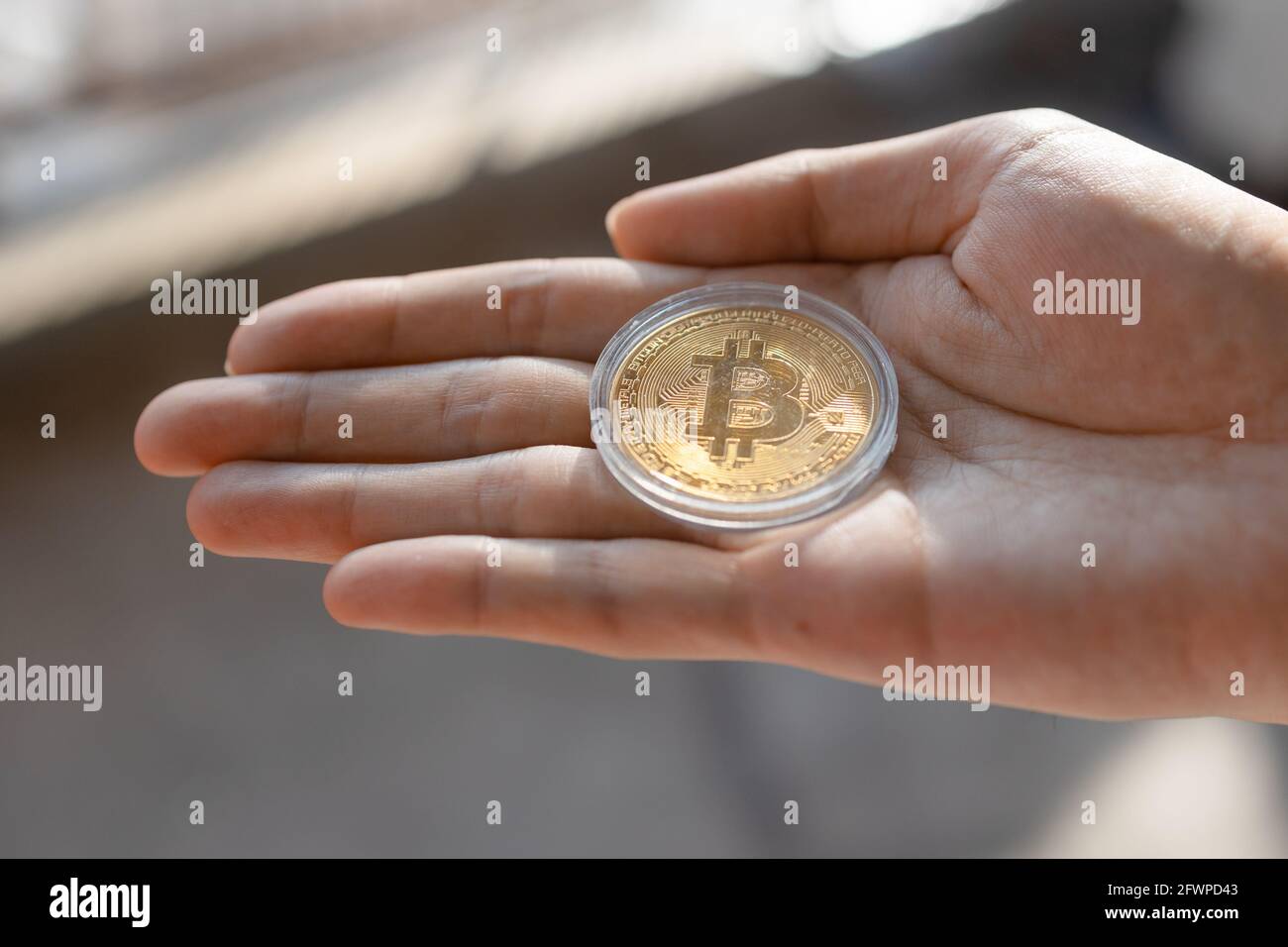 Young man holding BTC Bitcoin token on palm of hand - Cryptocurrency and  Digital asset concept Stock Photo - Alamy