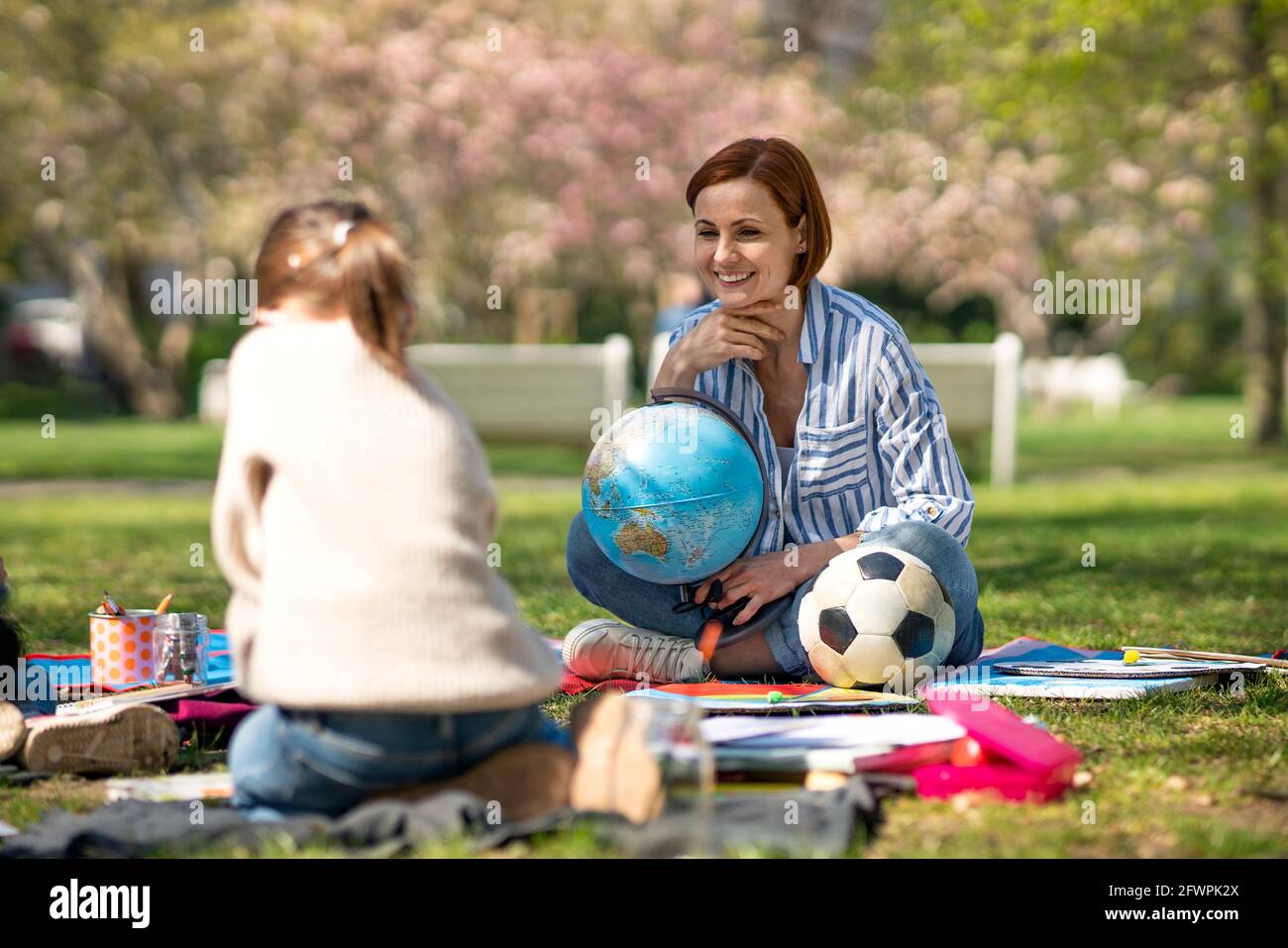 Teacher with small children sitting outdoors in city park, learning group education concept. Stock Photo