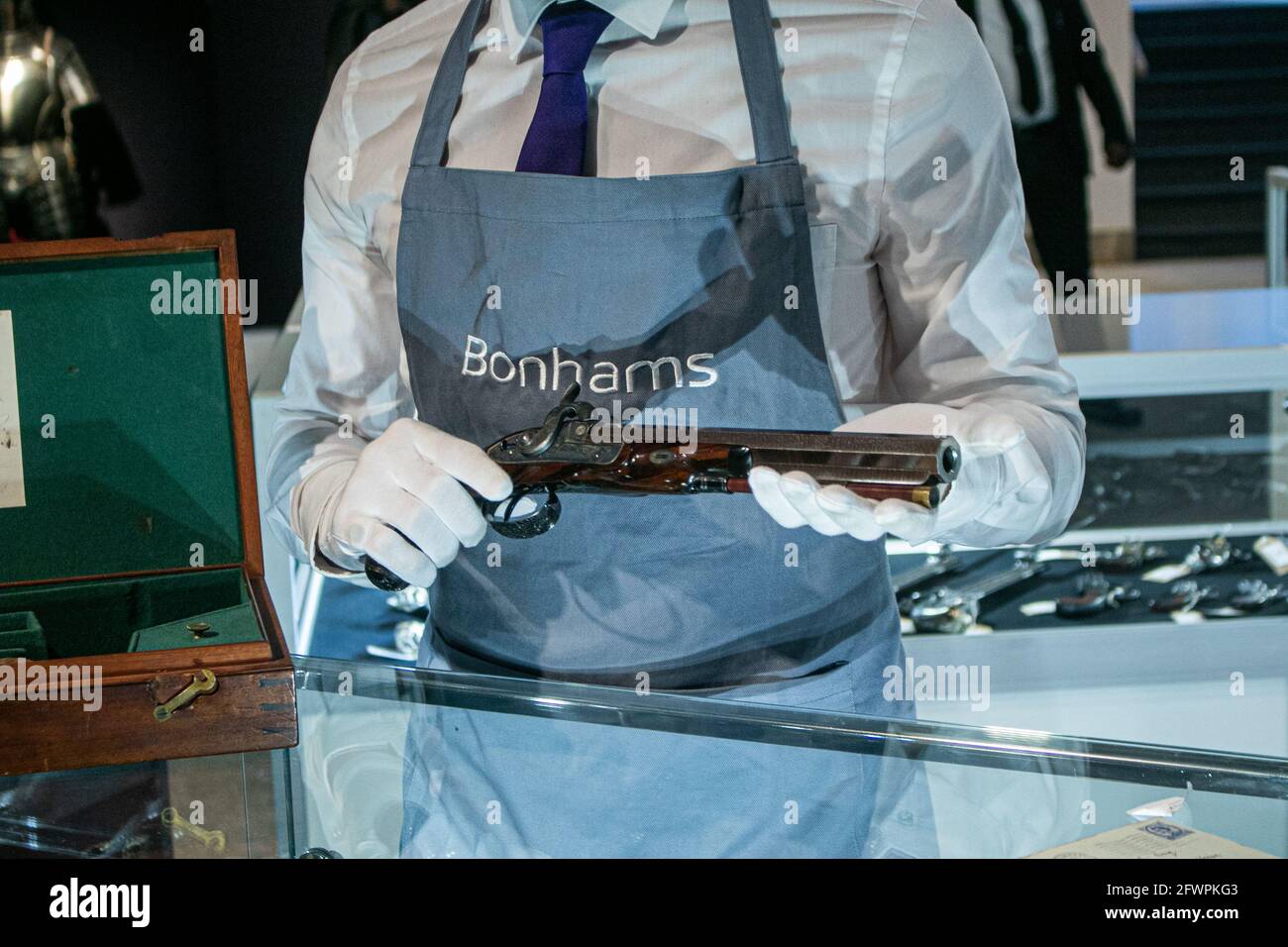 BONHAMS KNIGHTSBRIDGE LONDON 24 May 2021. A Bonhams  gallery assistant poses an exceptional percussion duelling pistol, by John Manton & Son, Dover Street during a press preview for Bonhams Antique Arms and Armour Sale. The sale will take place on 26 May at Bonhams Knightsbridge. Credit amer ghazzal/Alamy Live News Stock Photo