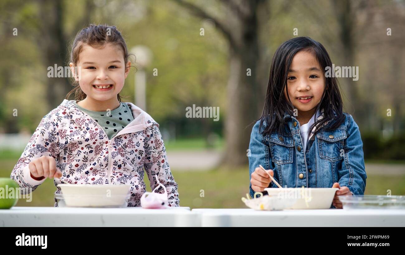 Small children eating lunch outdoors in city park, learning group education concept. Stock Photo