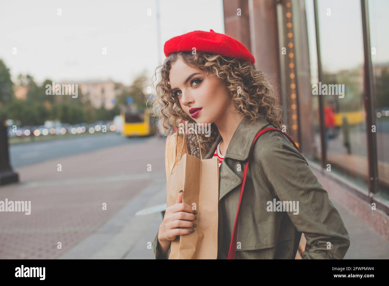 Cheerful young woman french model in red beret walking on city street ...