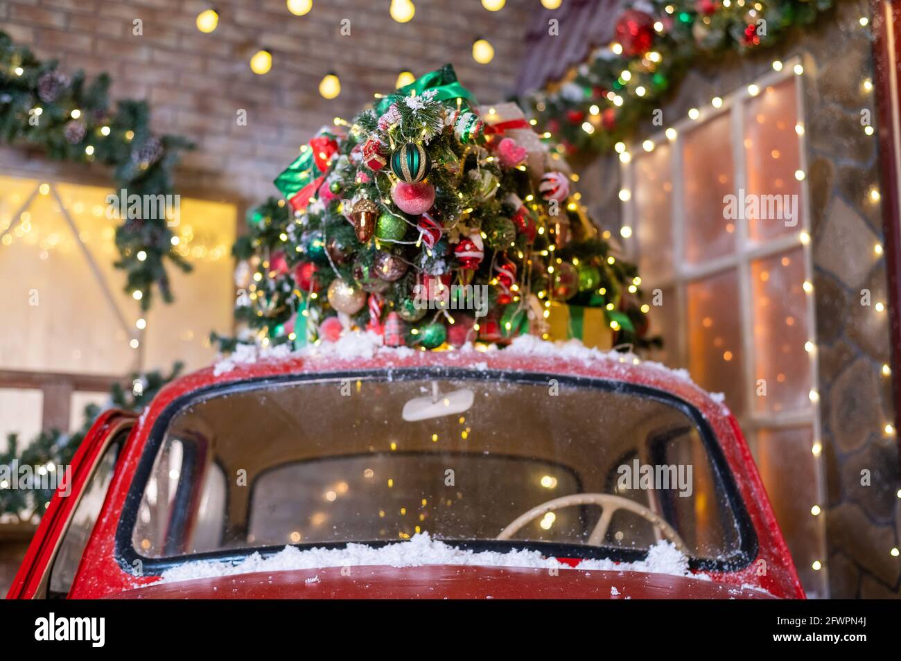 Christmas tree on a red classic car outdoors. Decorated santa 