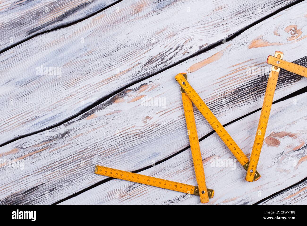 Yellow folding ruler on gray wooden background. Stock Photo