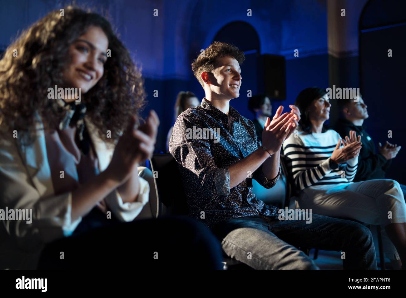 Group of people clapping while listening to presentation at conference. Stock Photo