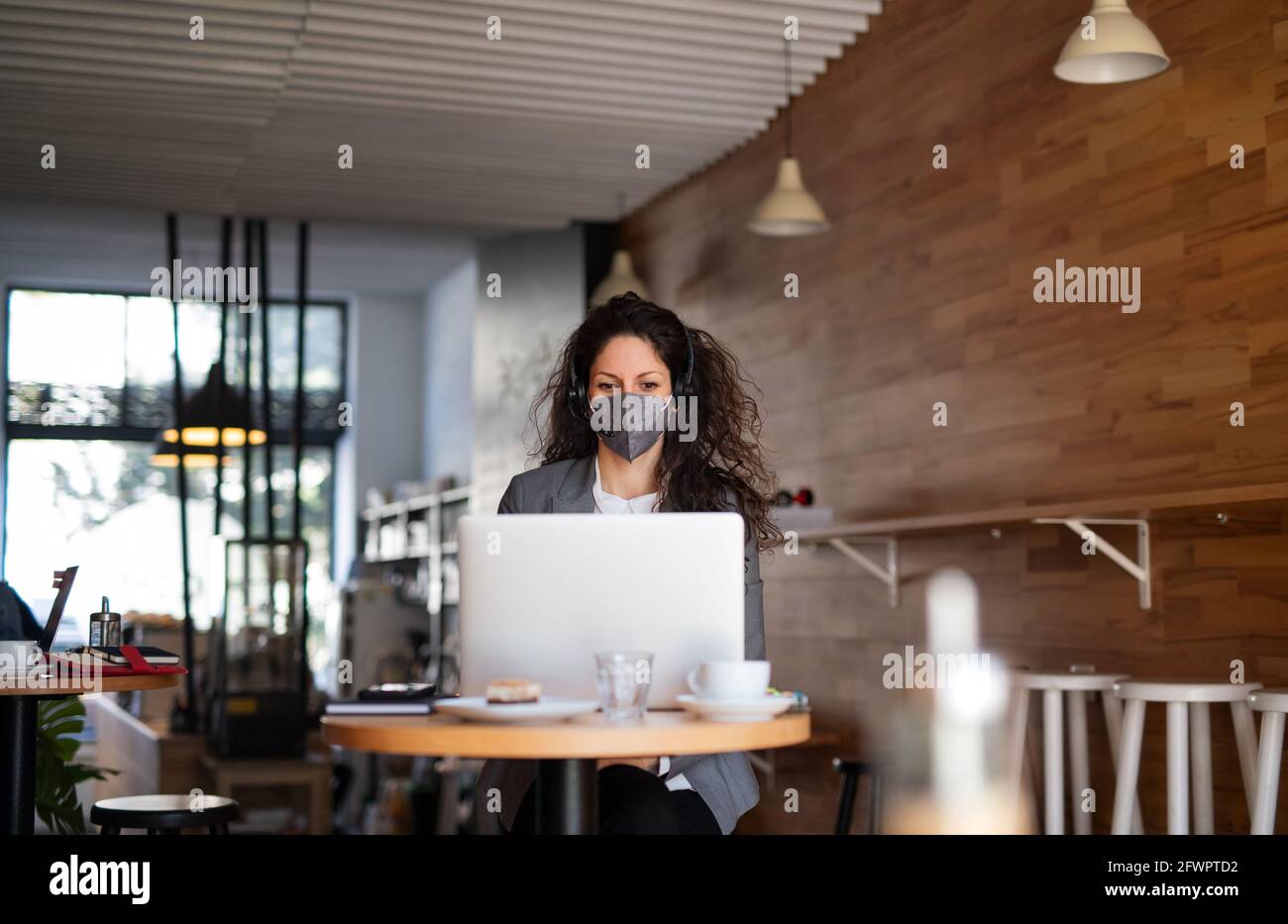 Businesswoman with laptop working in cafe, freelance work and coronavirus concept. Stock Photo