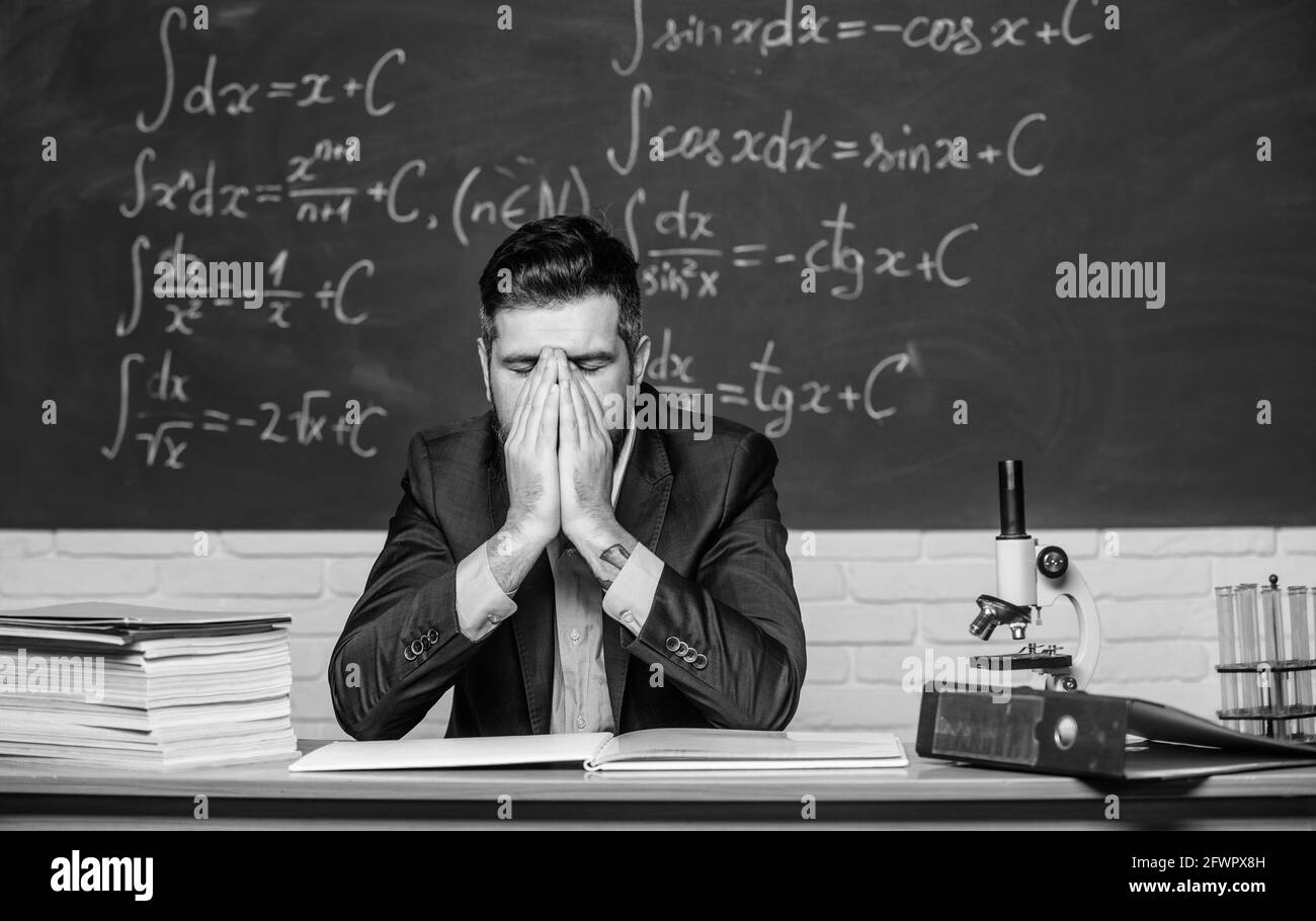 Teaching dumb students. Teacher mature man. Fed up. Man desperate teacher in classroom. No hope for better. Tired and exhausted. Difficult work Stock Photo