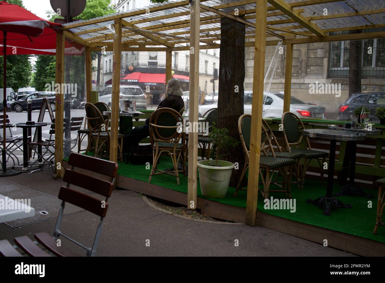 A man sits alone on the temporary terrace of a cafe in Paris after Covid-19 restrictions were lifted in 2021 - Le Montmartre Café, Rue Custine, 75018, Paris, France Stock Photo