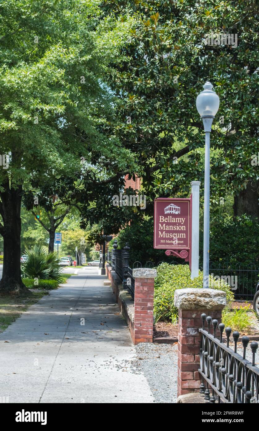 Tree covered sidewalk in historic downtown Wilmington, North Carolina with a historical sign for the location of the Bellamy Mansion Stock Photo