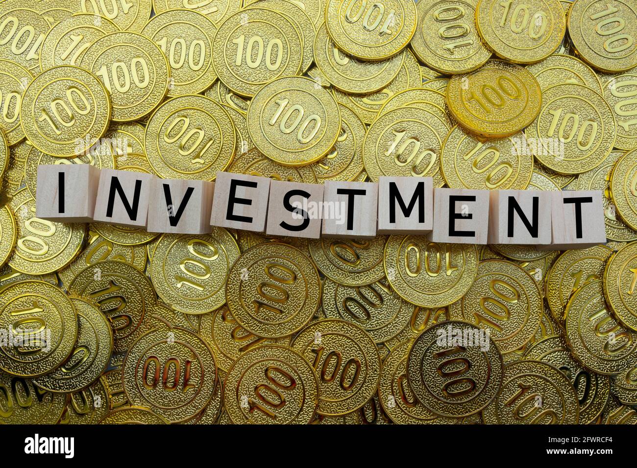 Investment text on wood block with a pile of gold coins Stock Photo - Alamy
