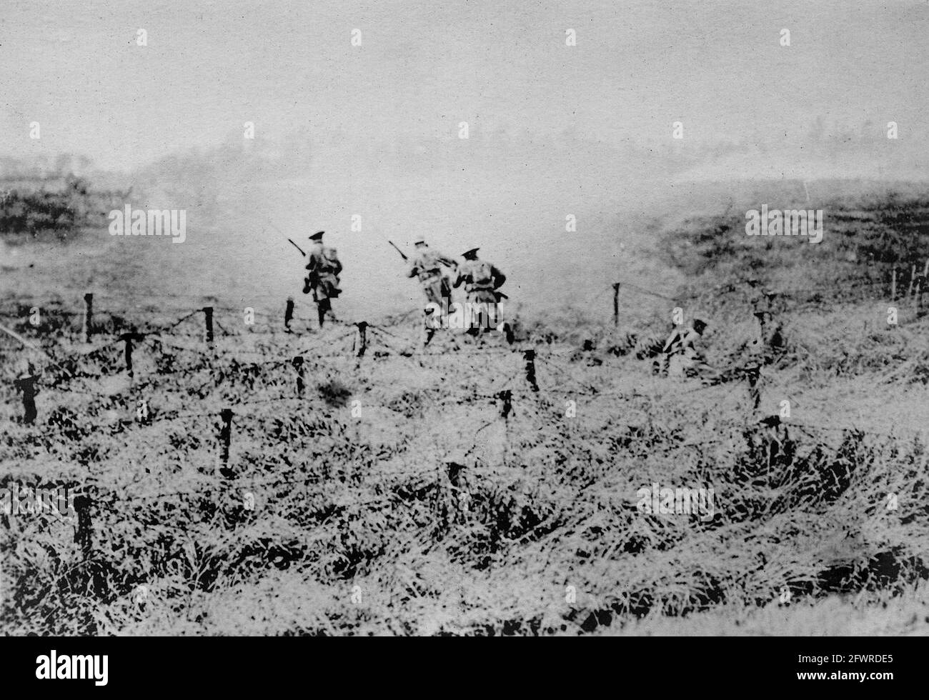 American infantry going ‘over the top’ a few seconds after ‘zero hour’. 1918. There is a fallen soldier on the right. Stock Photo