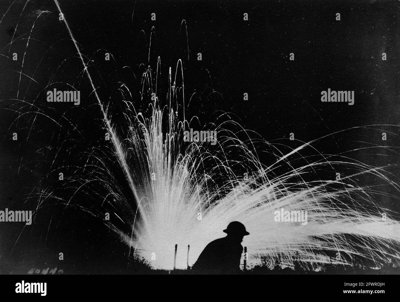 A phosphorous shell exploding in ‘no man’s land’ during a night attack. A soldier silhouetted against the blast is in danger of being observed by enemy snipers. France, 1918. Stock Photo