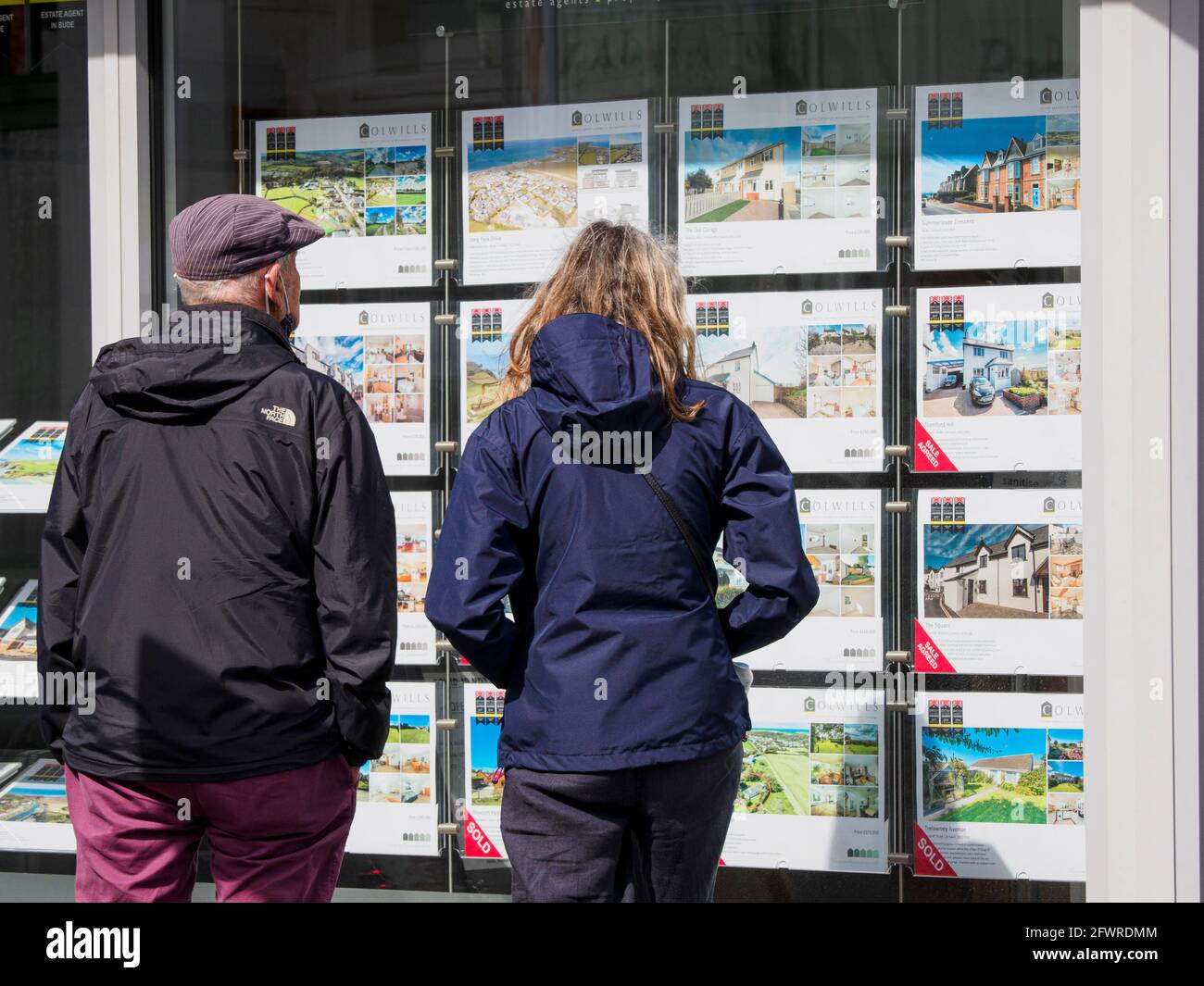 Couple looking at houses in an estate agent's window, Bude, Cornwall, UK Stock Photo