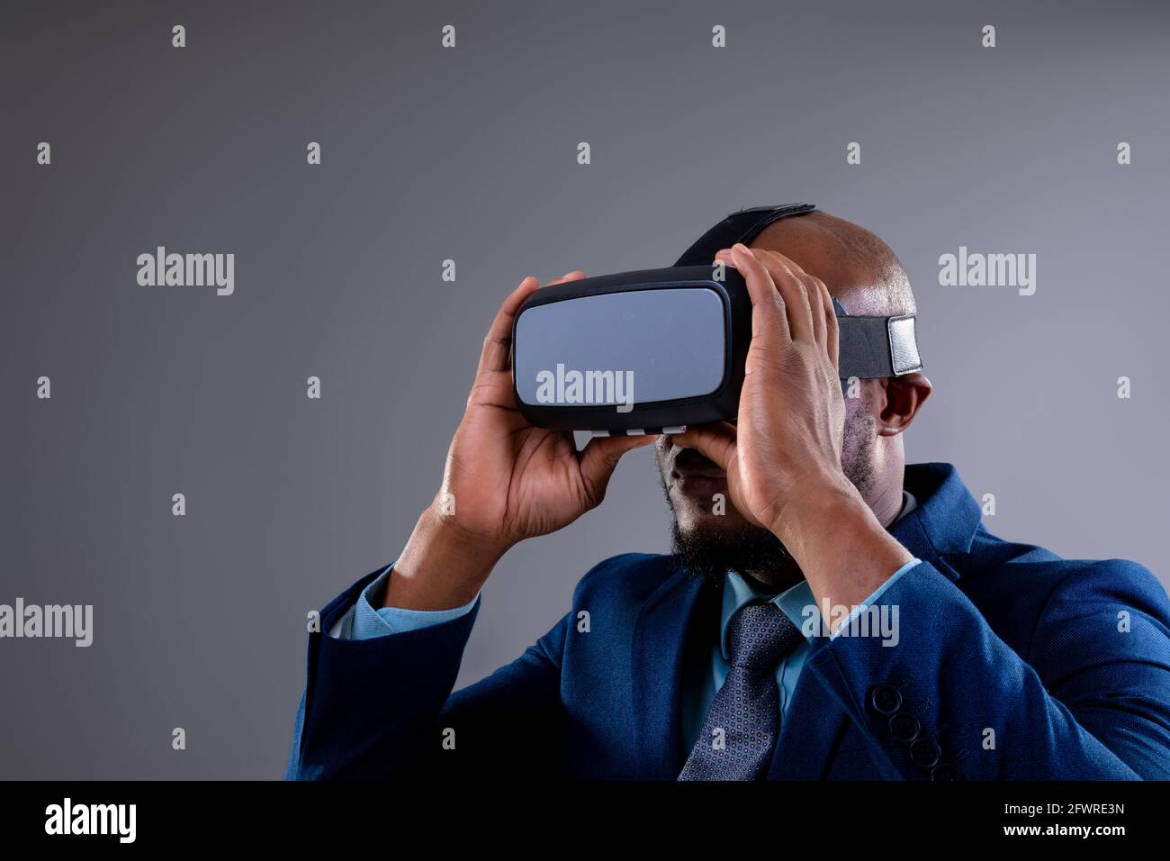 African american businessman wearing vr headset against grey background Stock Photo
