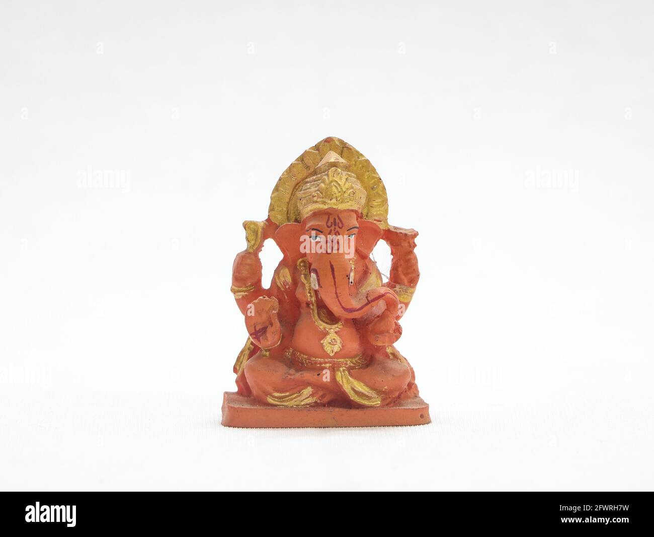 hindu god lord ganesh orange painted statue isolated in a white background Stock Photo