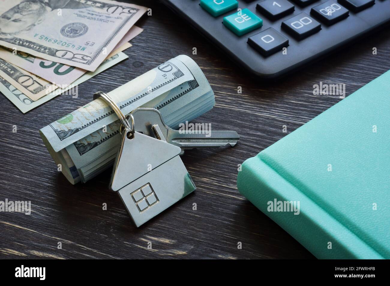 Money for rent. Roll of cash and key with tiny home. Stock Photo