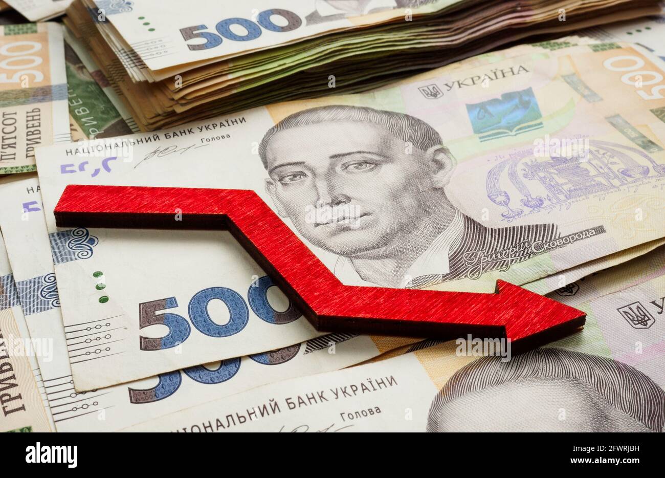 Financial crisis and inflation in Ukraine. Ukrainian money hryvnia and down arrow. Stock Photo