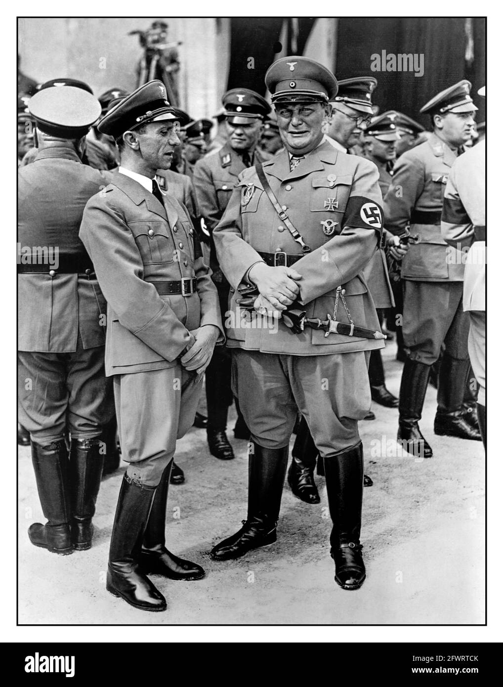1930s Propaganda Nazi photo of Dr Joseph Goebbels and Hermann Goering in uniform with jackboots wearing Swastika armbands standing together with other high ranking officers of the Nazi Party. Germany, 1936. Stock Photo
