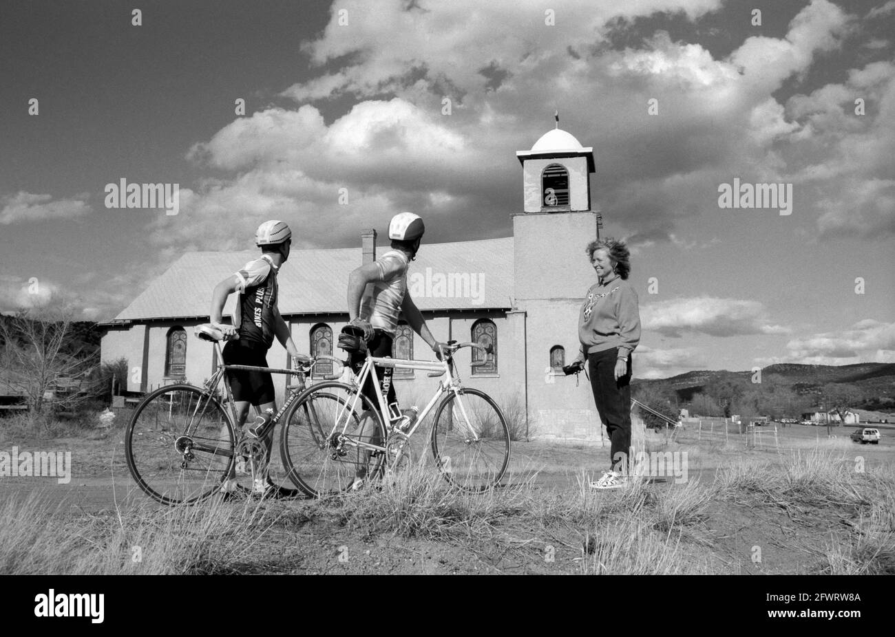 Bicyclists admire the historic Mission Chapel of Our Lady of Light, built in Lamy New Mexico in 1926. The chapel was abandoned in 1994 because of no priest or parishoners. Circa 1977. Stock Photo