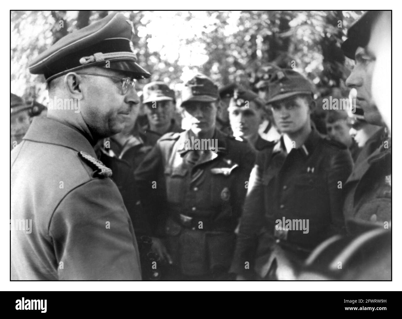 HIMMLER 1940's WW2 Heinrich Luitpold Himmler in conversation with soldiers of the Waffen SS  he was Reichsführer of the Schutzstaffel (Protection Squadron; SS), and a leading member of the Nazi Party (NSDAP) of Germany. Himmler was one of the most powerful men in Nazi Germany and a main architect of the Holocaust. Stock Photo