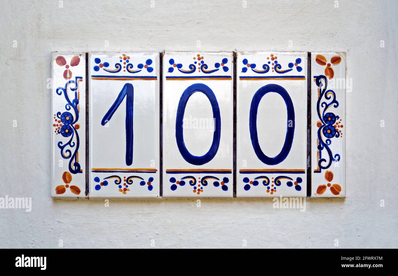 Street sign number 100 on a white wall Stock Photo