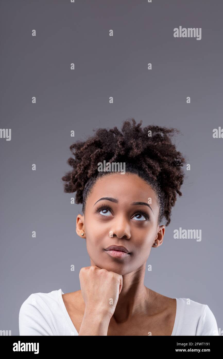 Thoughtful young Black daydreaming, planning new ideas, making a decision  or solving a problem woman with hand to chin looking up on a grey studio  bac Stock Photo - Alamy