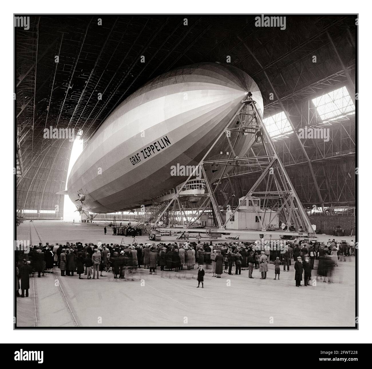 GRAF ZEPPELIN 1930’s Guests watch as the Graf Zeppelin moored in a large hangar at Akron, Ohio USA is prepared for its return air trip to Europe Oct. 27, 1933. Graf Zeppelin provided a commercial passenger and mail service between Germany and Brazil via USA for five years. When the Nazi Party came to power, they used it as a propaganda tool. It was withdrawn from service after the Hindenburg disaster in 1937, and scrapped for military aircraft production in 1940. Stock Photo