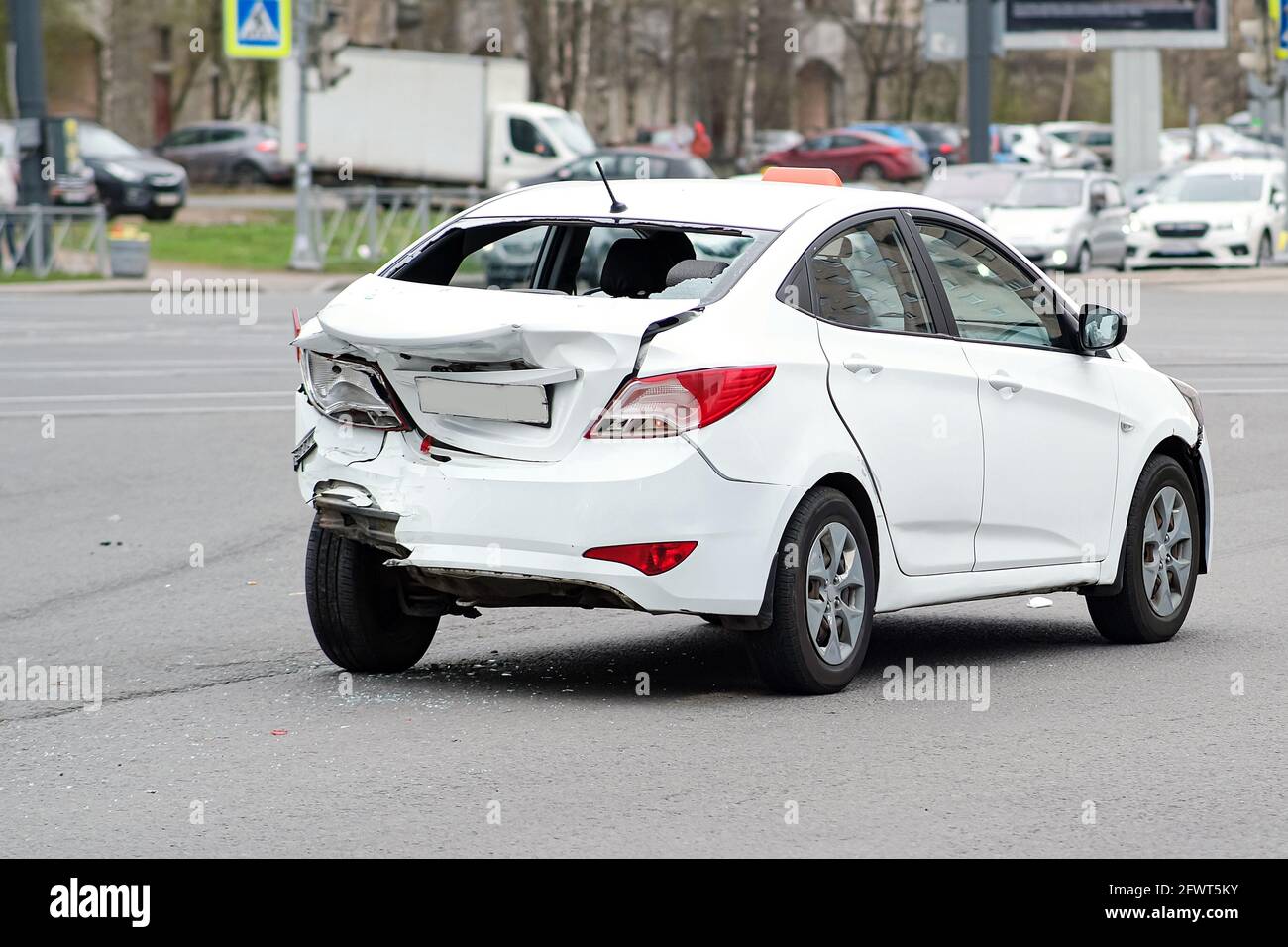 Collision of cars. The white taxi car suffered severe damage to the rear of the body. Broken