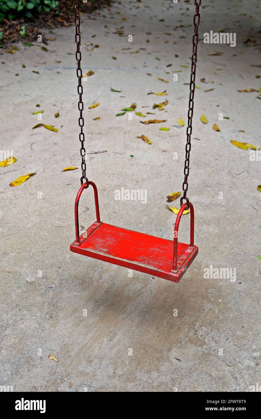 Red wooden swing hanging on chains Stock Photo Alamy