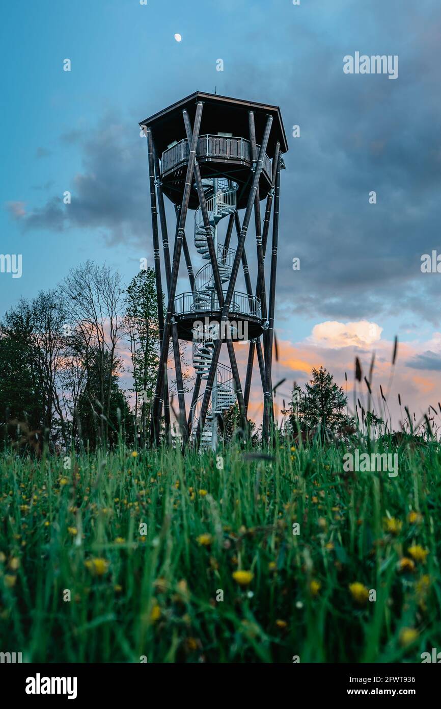 Lookout tower called Na Vetrne Horce at sunset, Broumov region,Czech Republic.Wooden tower with spiral staircase on blooming meadow fresh spring scene Stock Photo