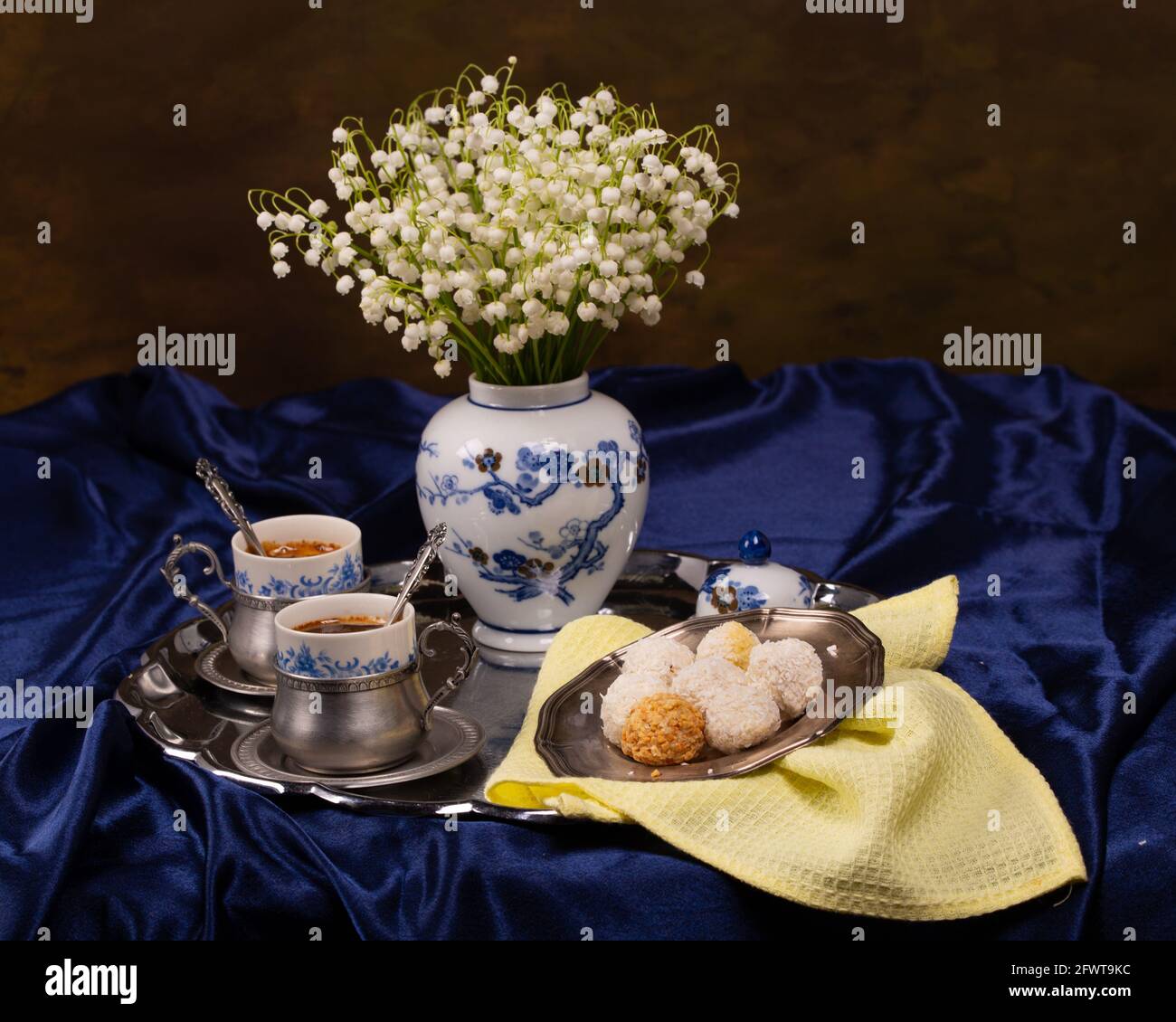Still life with a bouquet of lilies of the valley and cups of coffee on ...